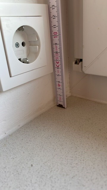 Elektrische Steckdose neben Massband in einer Innenraumnische