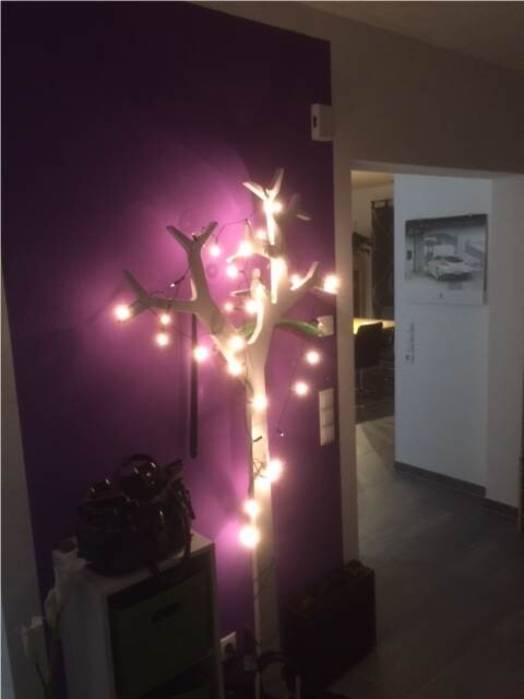 Decorative light tree with string lights in front of a purple wall in the living room.