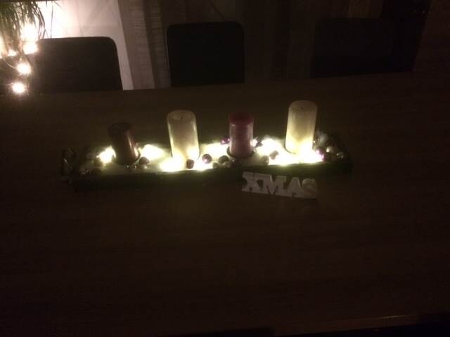 Table decoration with lit candles on wooden table, warm light, XMAS lettering