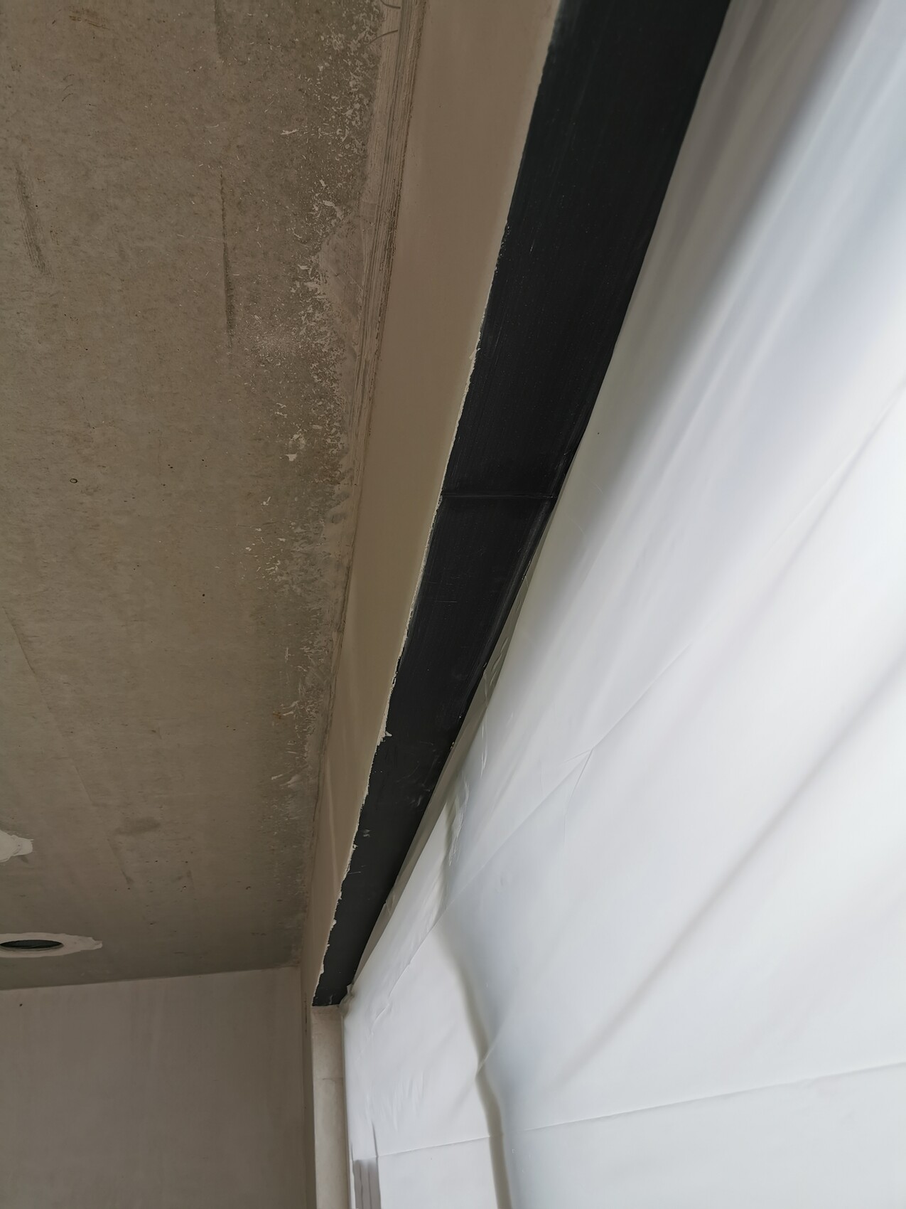 Interior: concrete ceiling on the left, dark beam in the middle, white tarpaulin on the right.