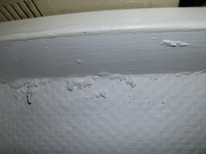 Damp wall with peeling plaster under the bathtub edge