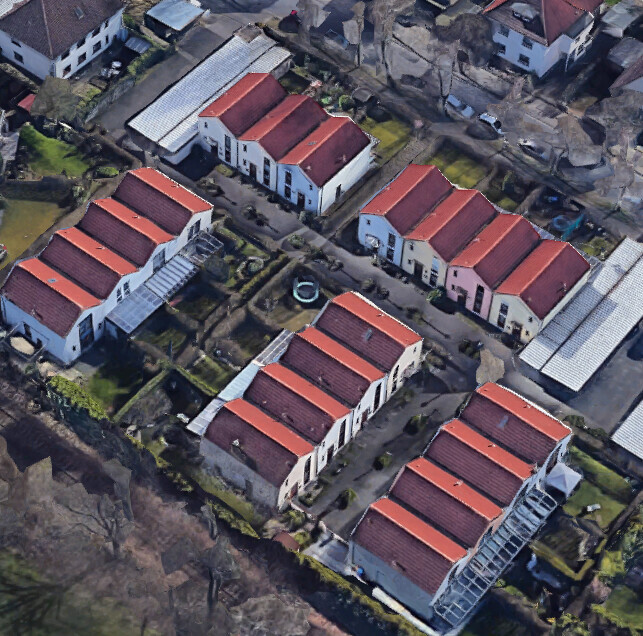 Bird's-eye view of a residential area with terraced houses, red tiled roofs, and small gardens.