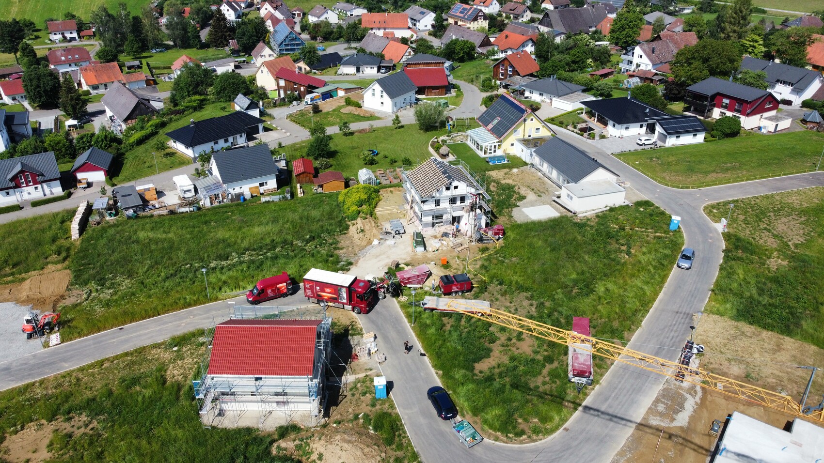 Aerial view of a residential area with a construction crane and shell construction work