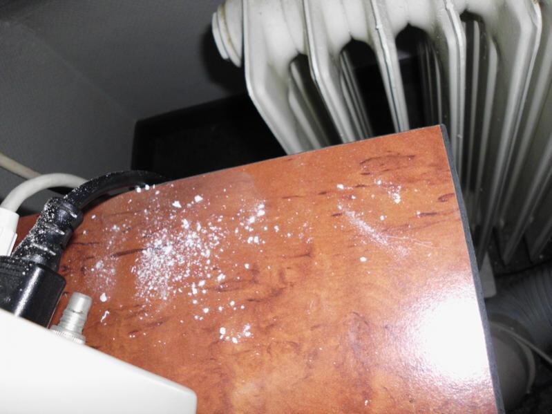 Close-up of a wooden surface with dust particles in front of a radiator.