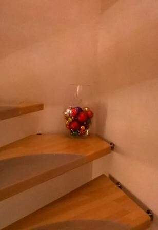Small wooden staircase section with glass vases filled with red and gold Christmas baubles.
