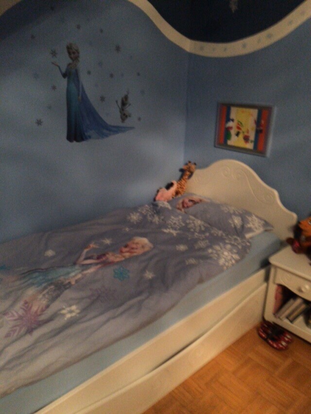 Small children’s room with Elsa wall decoration, light blue bedding, white bed frame, and nightstand.