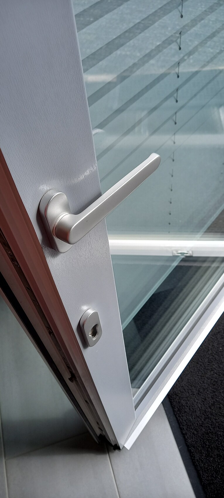 White door with silver lever handle and lock, glass window in background.