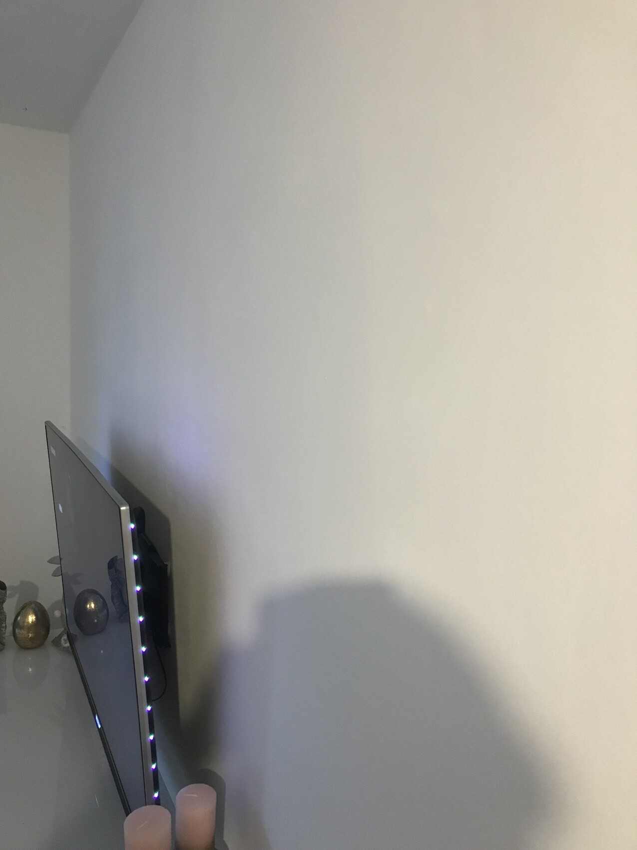 Flat-screen on the left wall with LED light strip, candles and decorations below.