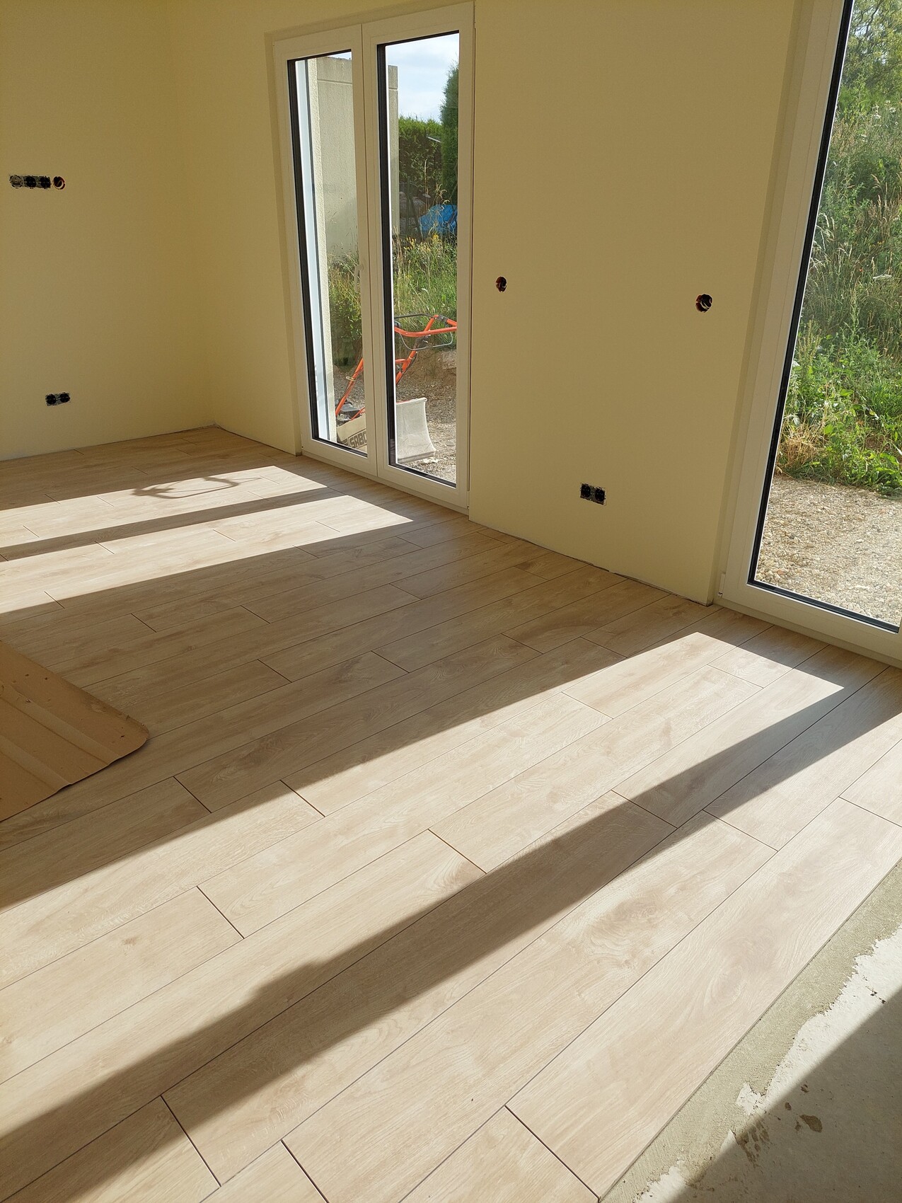 Bright living room with large windows and wood-look floor covering.