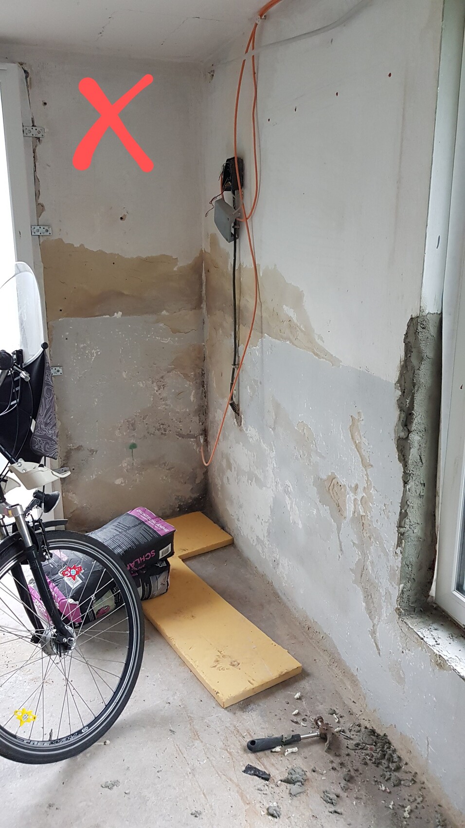 Renovation area inside with exposed pipes, construction debris, and a red X.