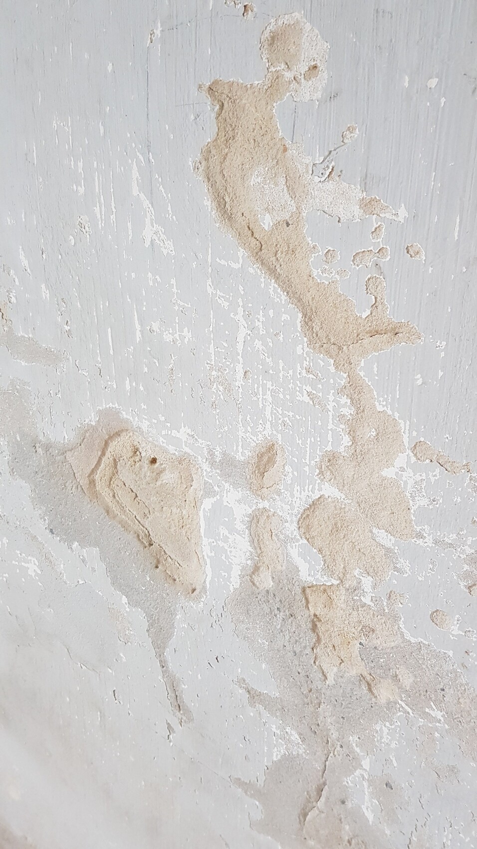 Wall with peeling plaster; beige stains on white surface.