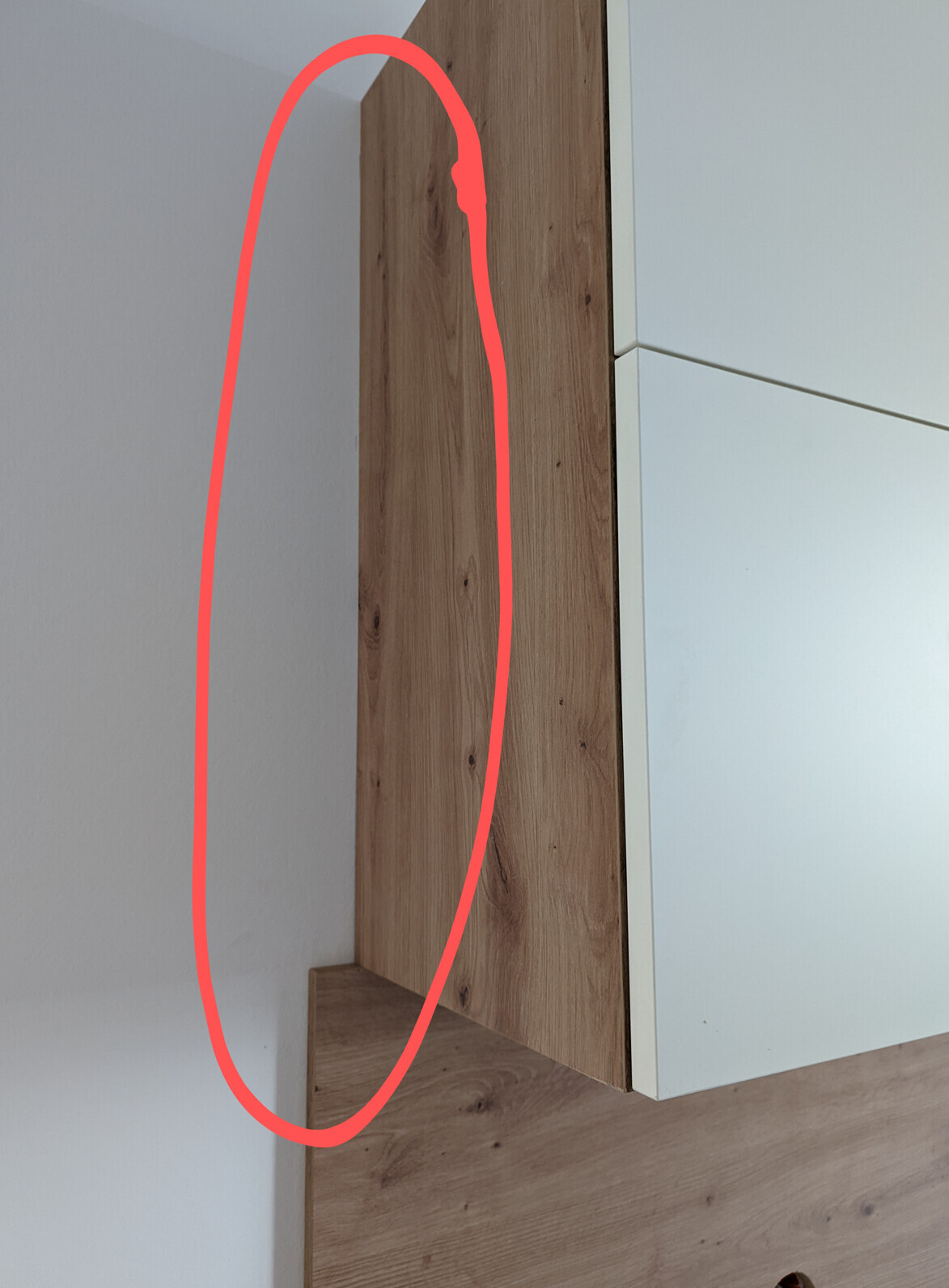 Vertical wood wall paneling next to a white cabinet in a room corner.