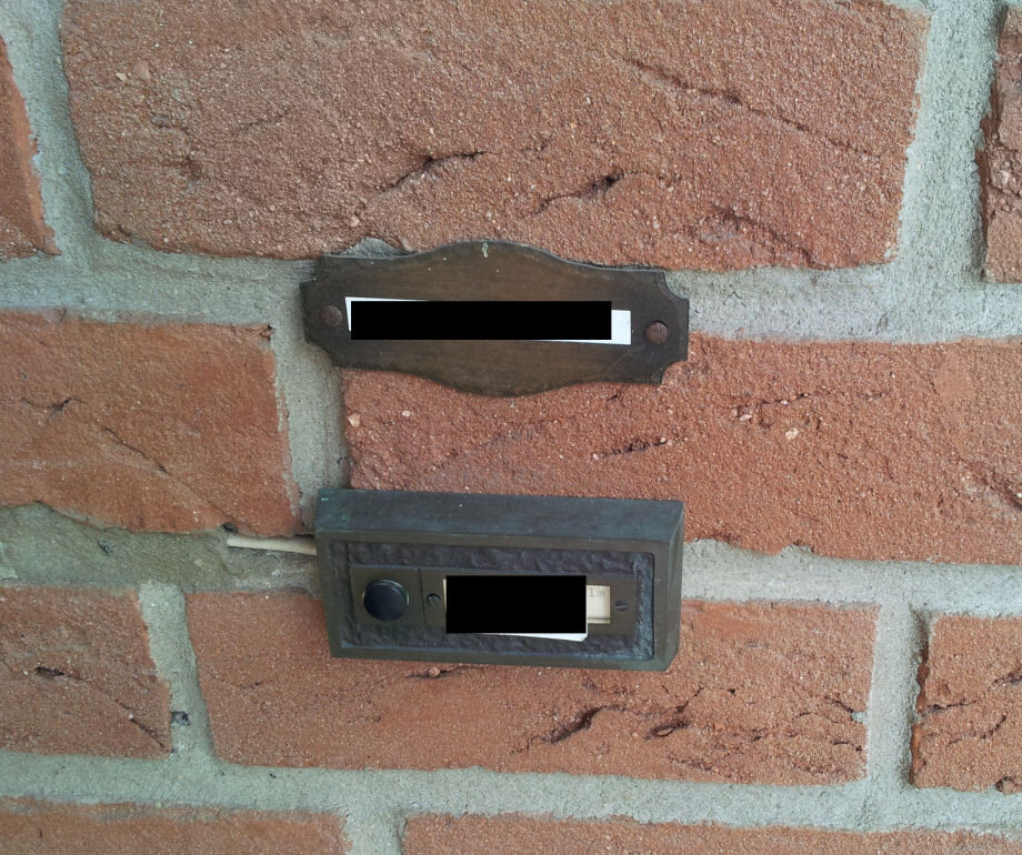 Exterior wall made of red bricks with mailbox and intercom at the entrance
