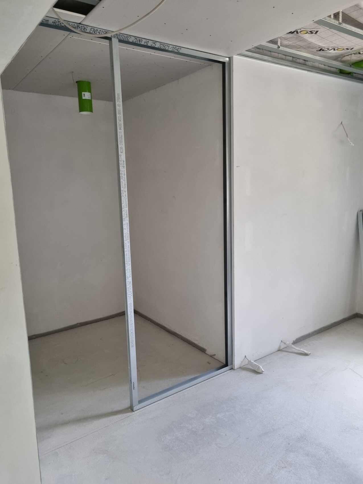 Unfinished interior with metal stud wall, open door; measuring rod in the niche.