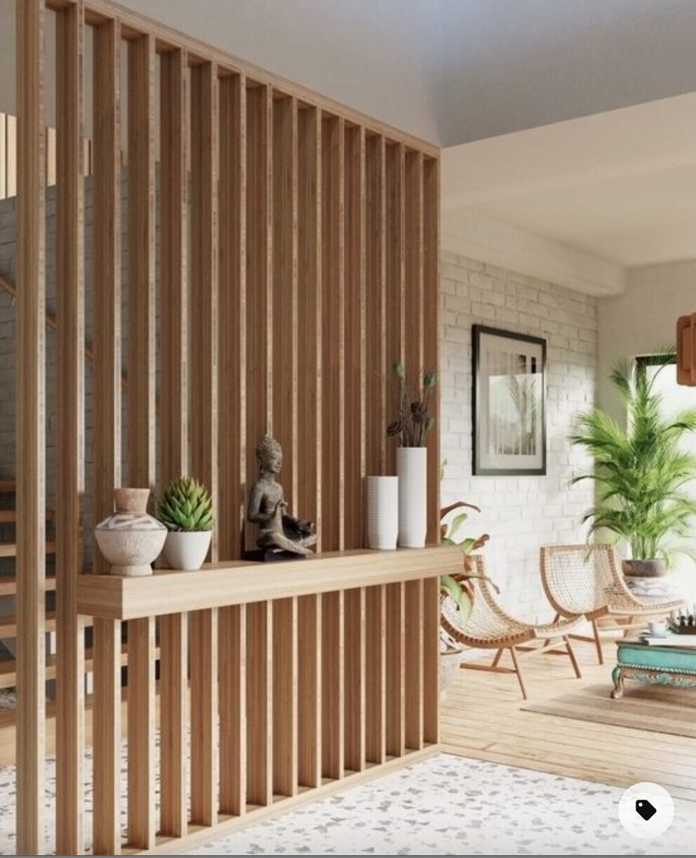 Living room with wooden partition, console table, Buddha statue, vases, plant, and rattan chair.