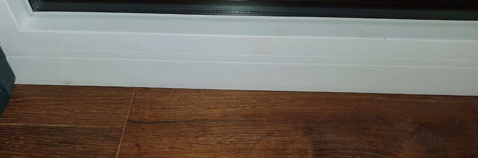 White baseboard over dark wood floor with wood grain.