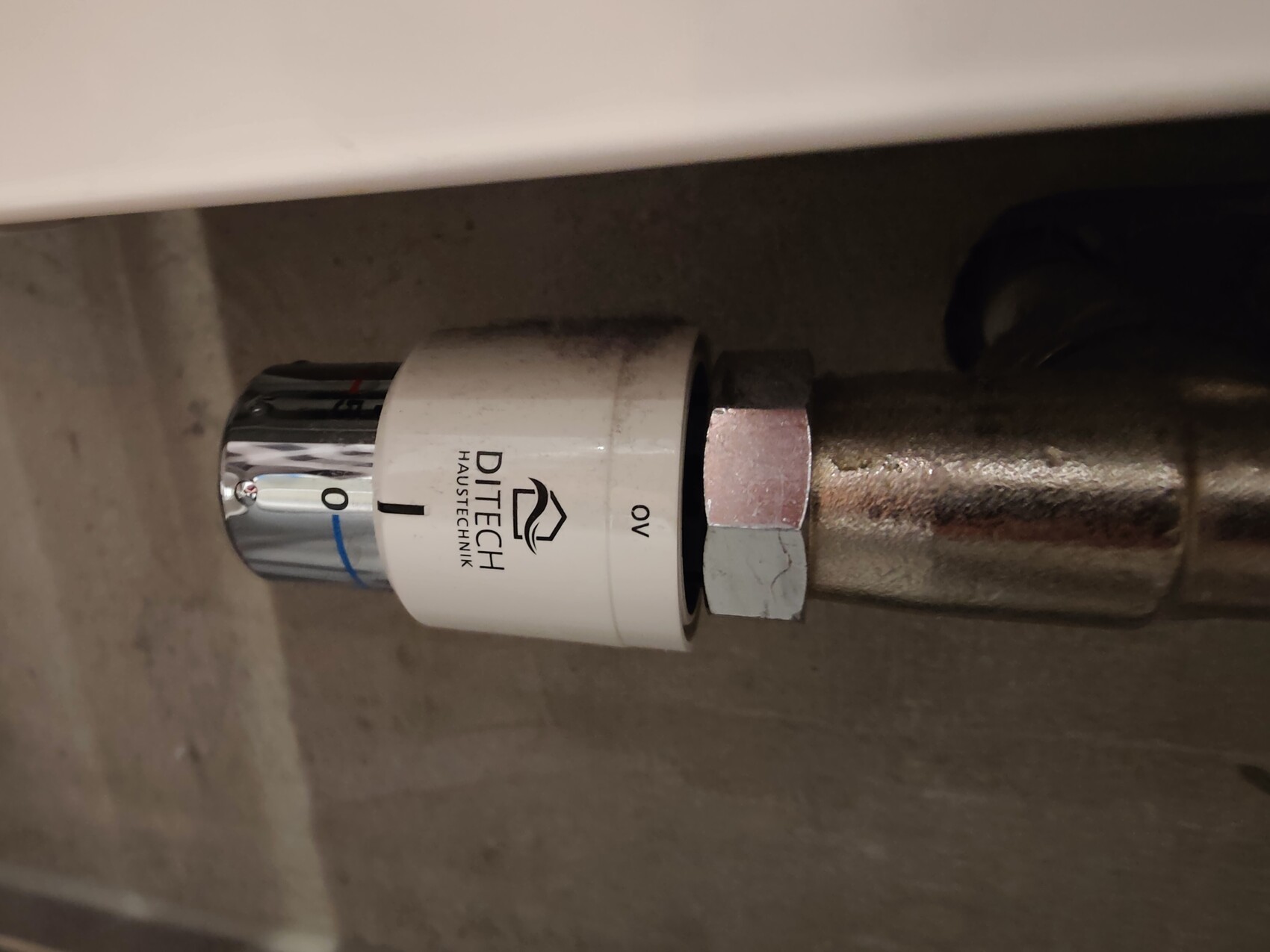 White DITECH building services adapter on a metal pipe connection with union nut.