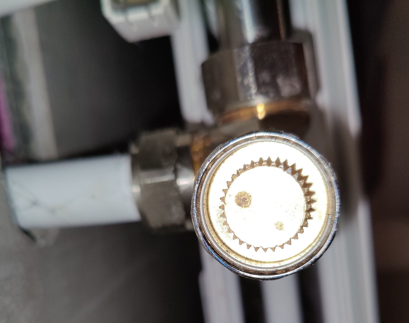 Close-up of a round adjustment knob with serrated inner ring on a machine.