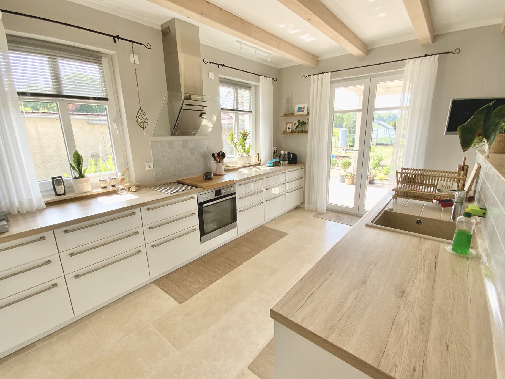 Modern kitchen with white cabinets, wooden countertop, extractor hood, and large windows