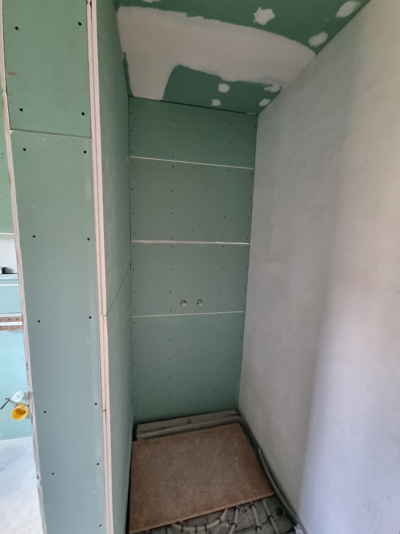 Shell niche with green drywall panels on walls and ceiling; uneven floor.