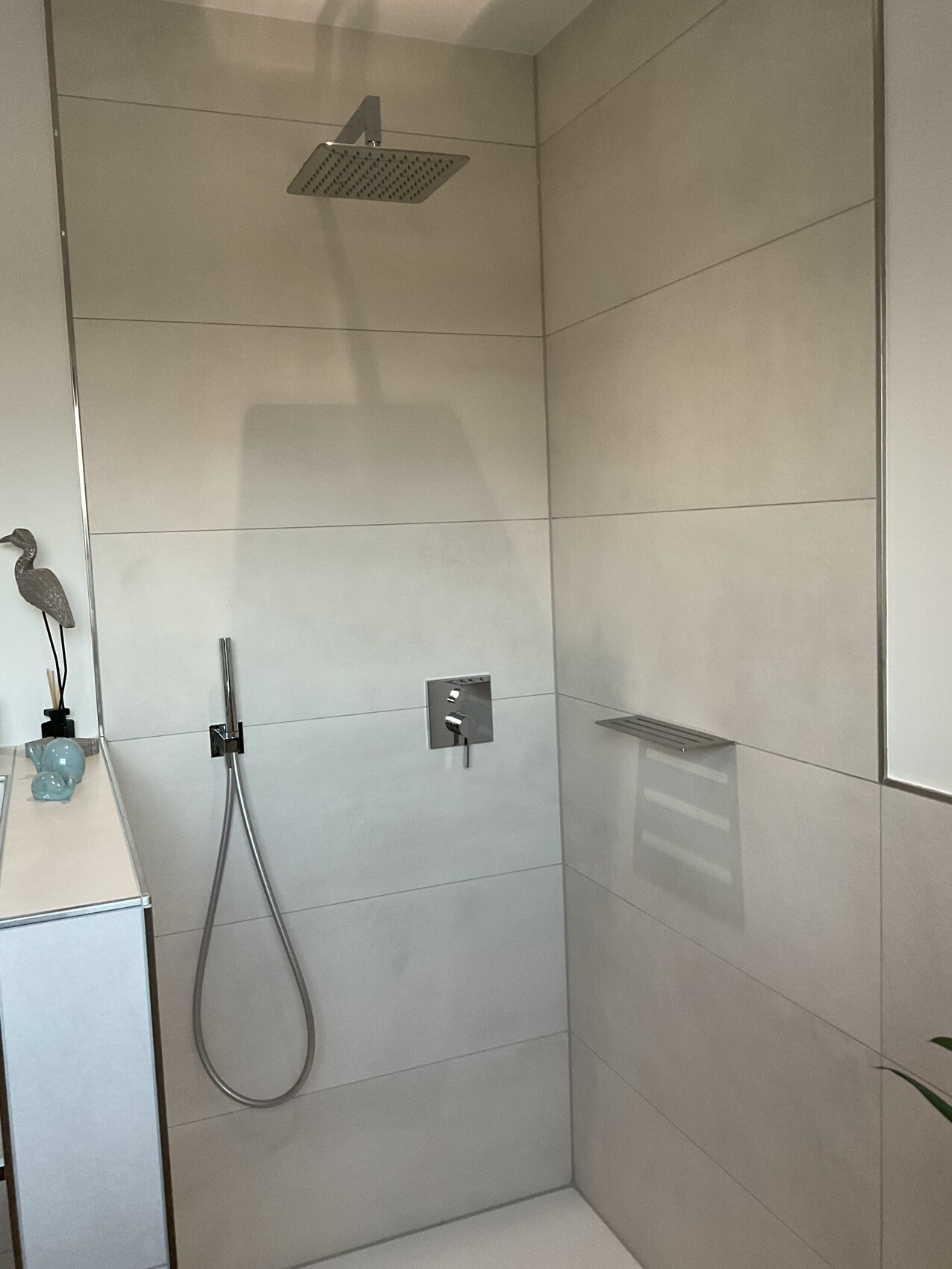 Modern walk-in shower: large square rain shower head, handheld shower, and fittings.