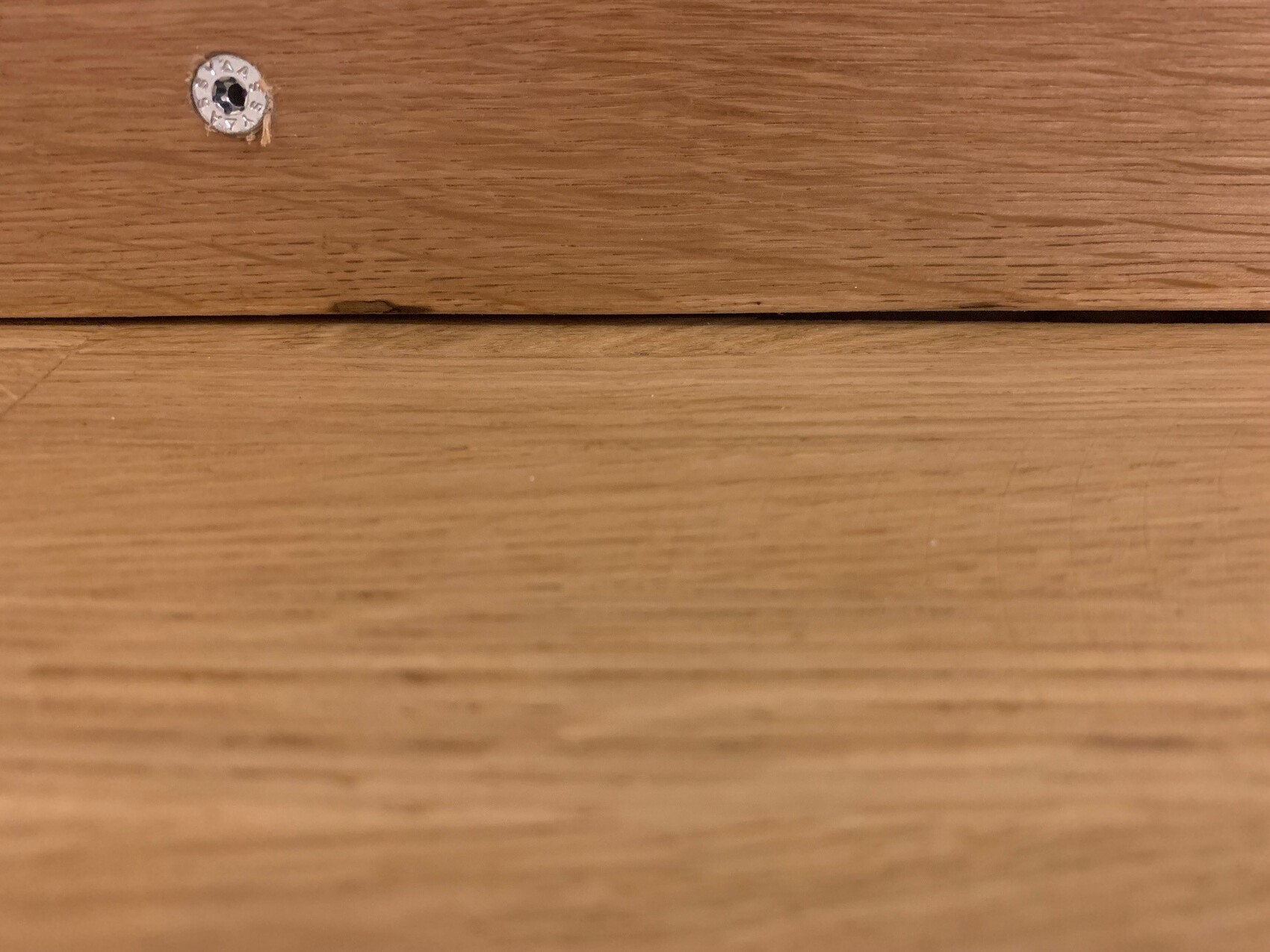 Close-up of a wooden surface with a small silver screw head top left