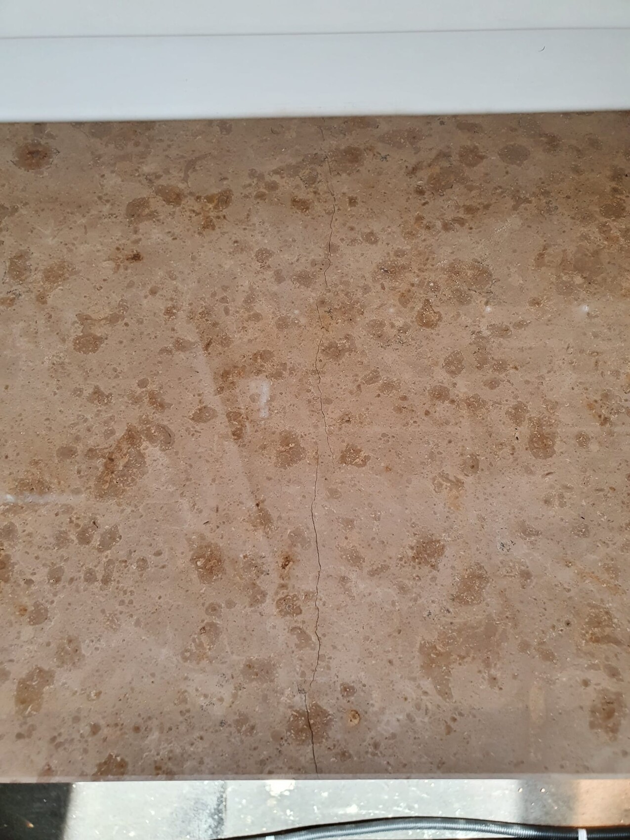 Brown, speckled floor with central crack line; metal edge visible at the bottom