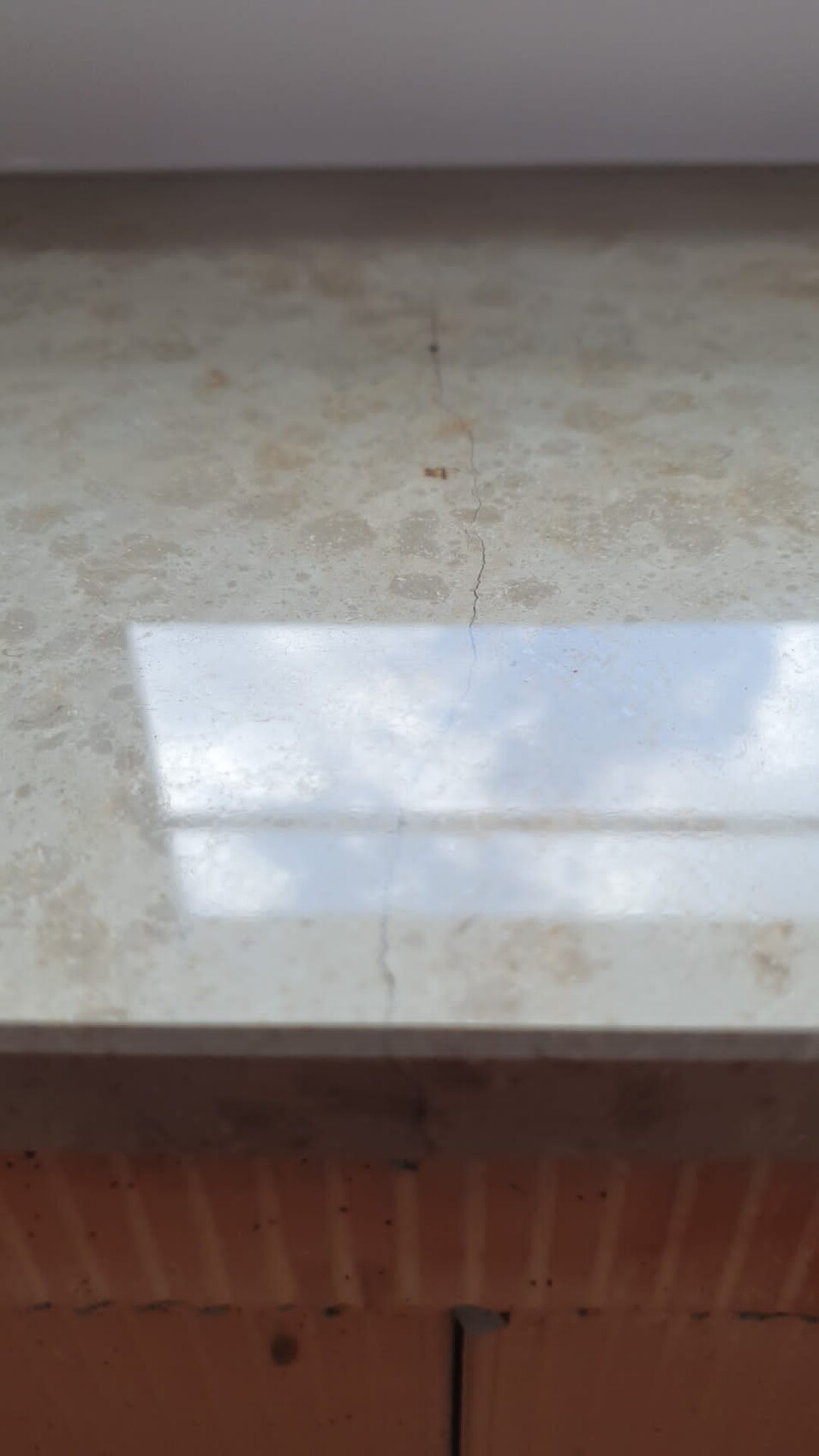Light stone worktop with fine hairline crack in the middle and reflection