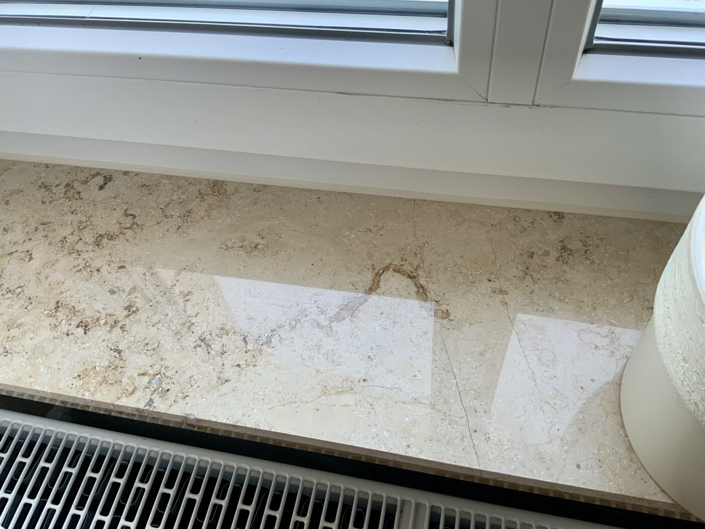 Light-colored stone window sill above radiator; a bucket is visible on the right.
