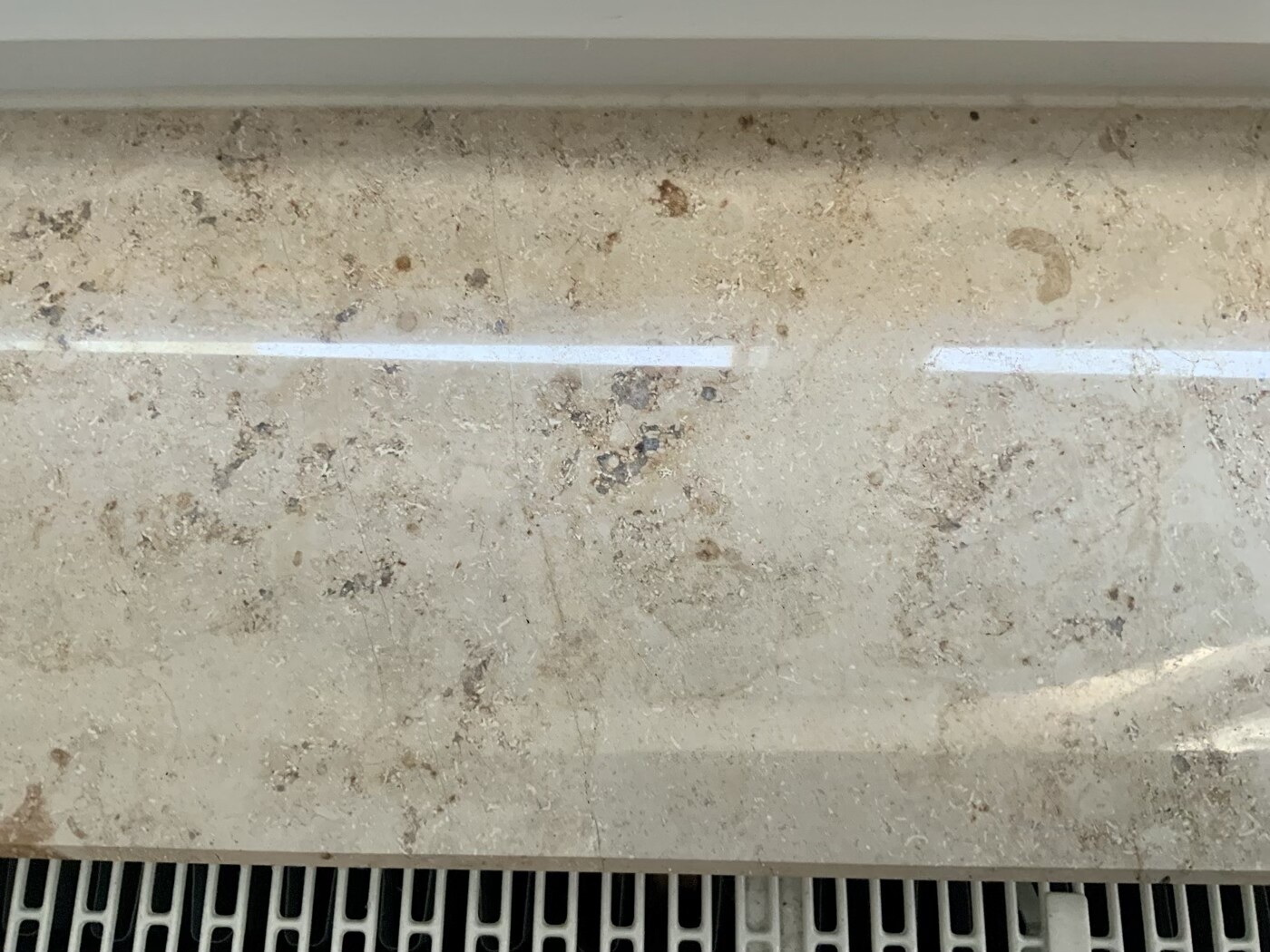 Dirty beige stone slab with stains; ventilation grille visible at the bottom.