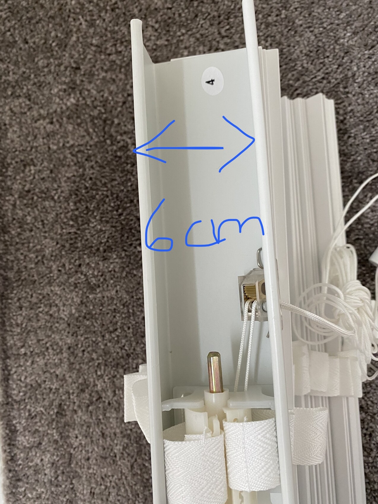 White vertical blind profile with cords; blue arrow marking shows 6 cm distance.