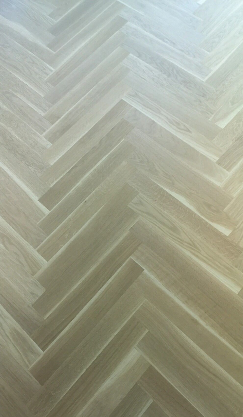 Light wood floor in herringbone pattern made of narrow boards.