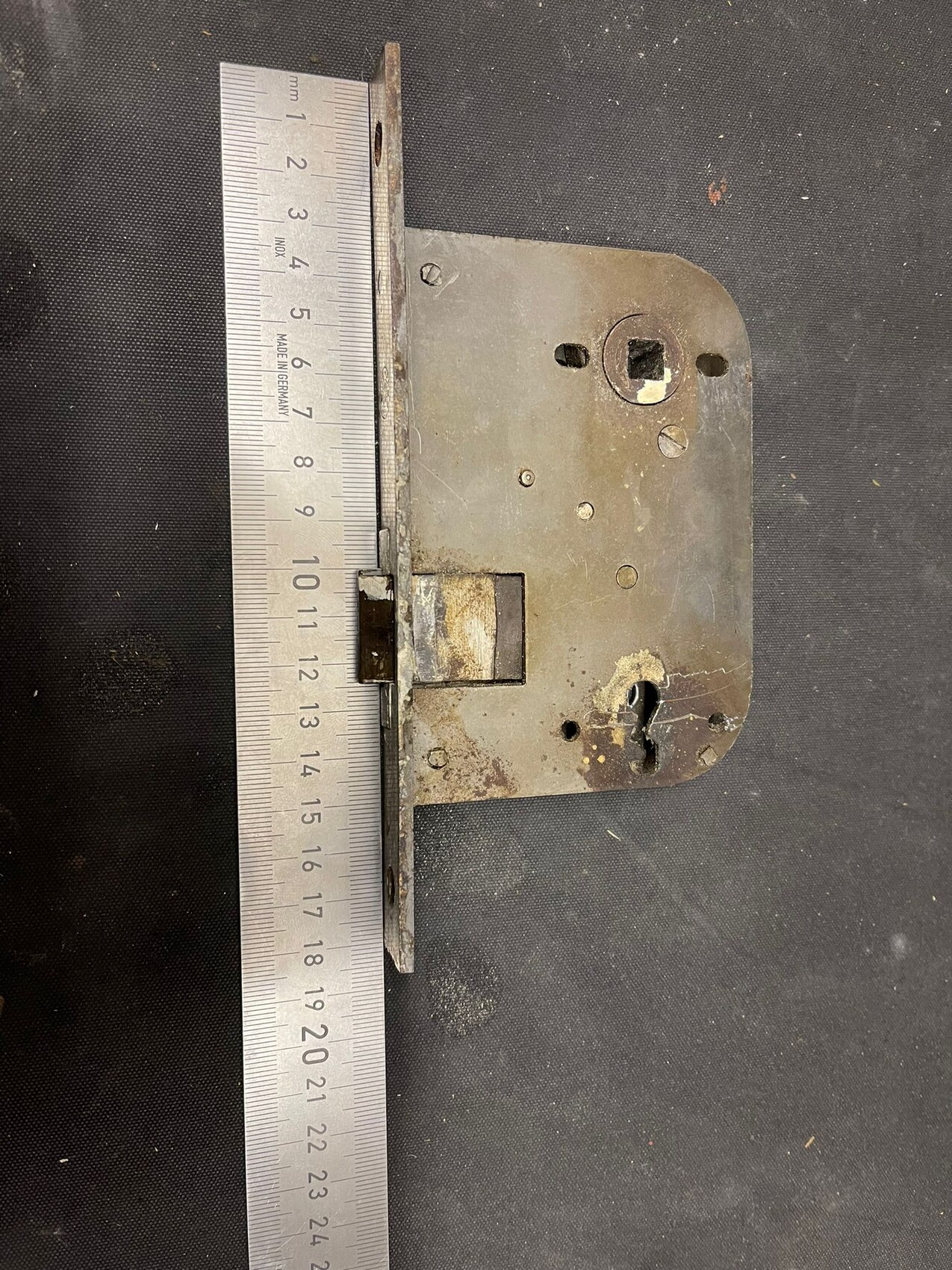Rusted metal door lock next to a cm ruler for size reference.