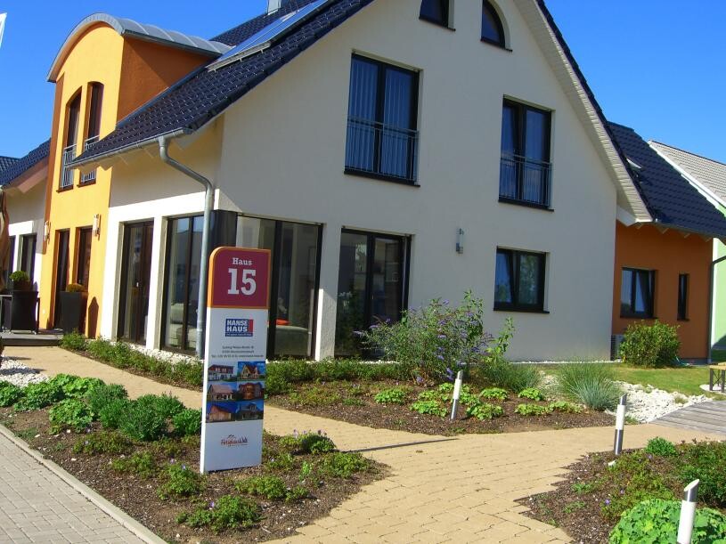 Moderne Hausfront mit Gartenweg, Signage Haus 15 und großen Fenstern.