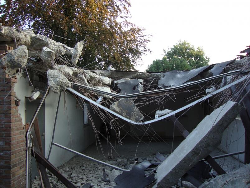 Collapsed interior with roof debris and concrete remains on construction site