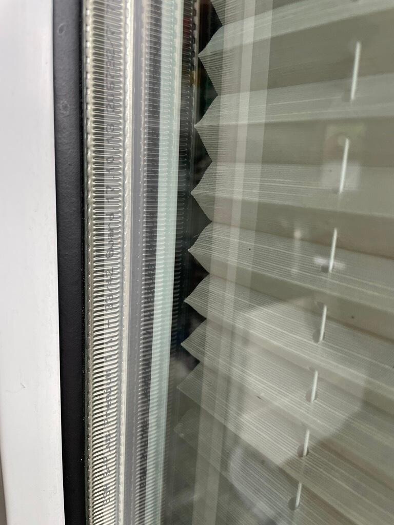 Close-up of a window with horizontal interior blinds and seal on the frame