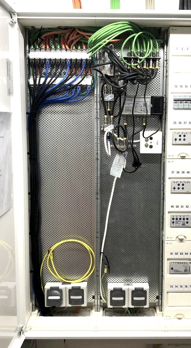 Electrical distribution cabinet with many colored cables and power strips.