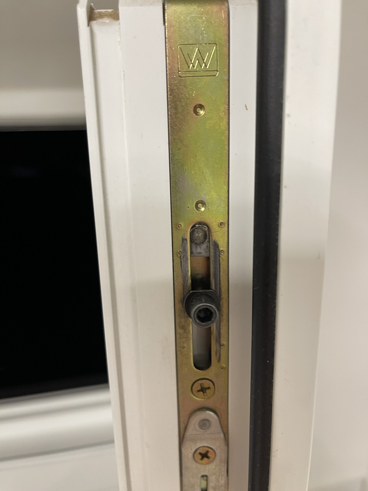 Close-up of a brass strike plate with screws in the door frame.