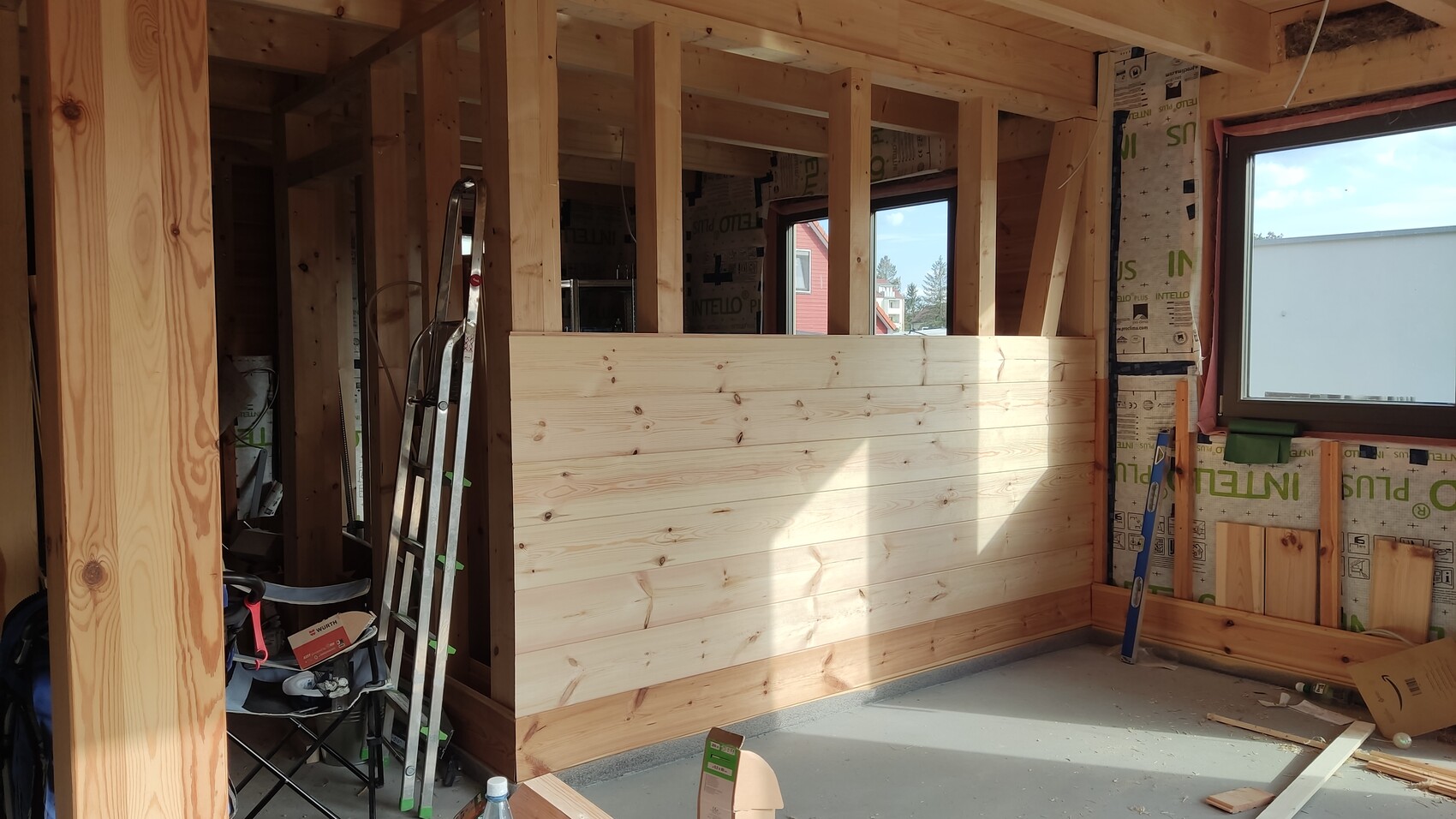 Interior view of a shell construction with timber frame, wood wall panels, ladder and window.