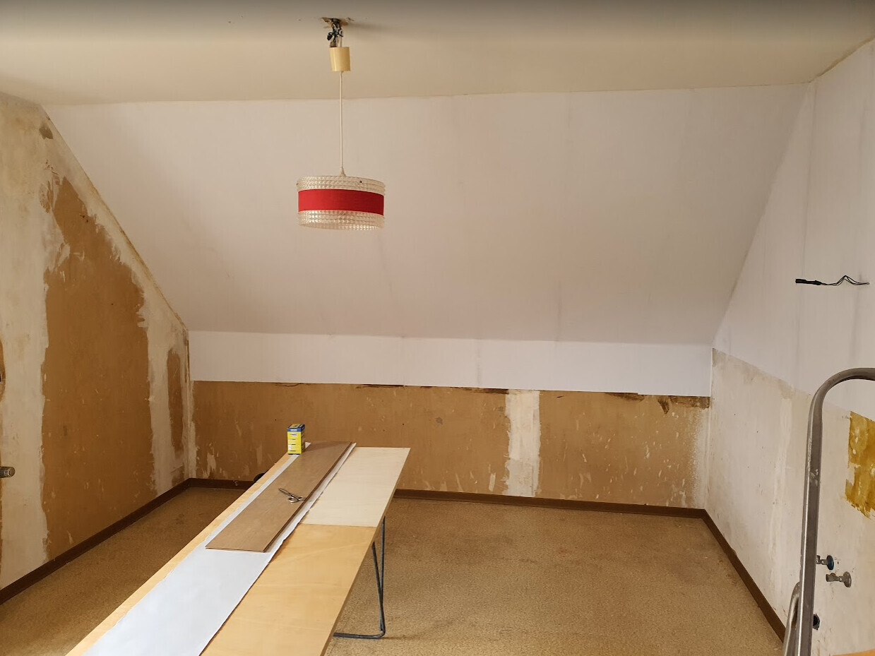 Renovation room in the attic with red pendant light, boards on a table.