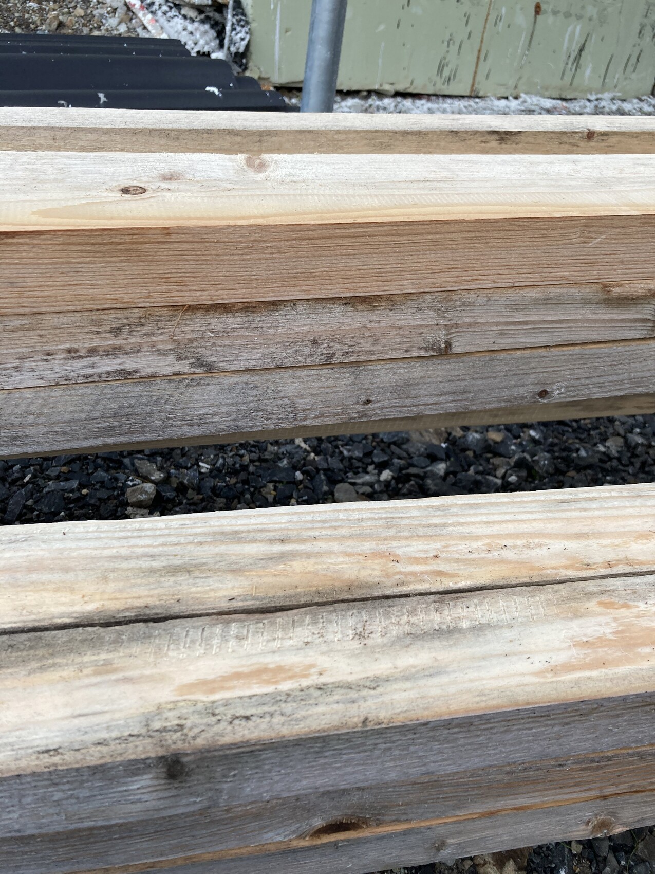 Several stacked untreated wooden battens outdoors, frosty and rough.