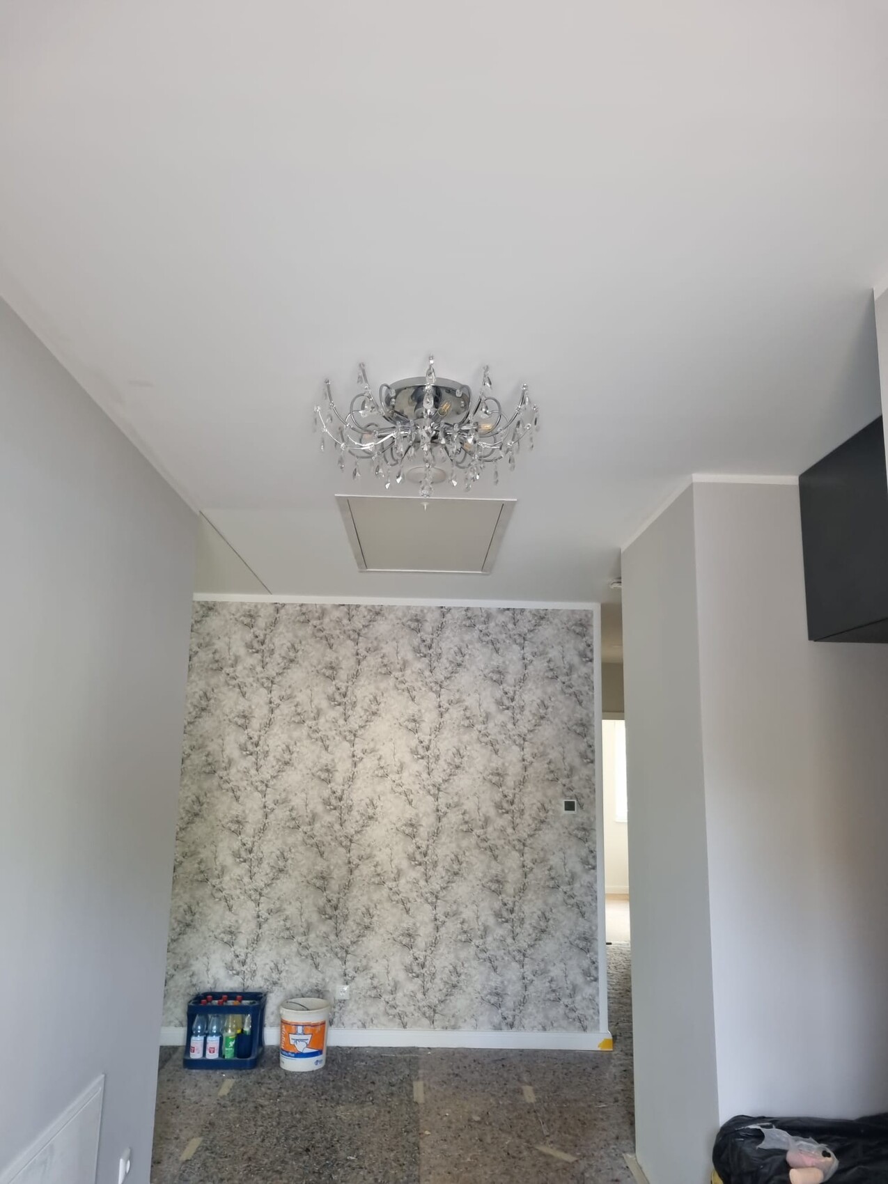 Living room with crystal chandelier, patterned wallpaper, and renovation work