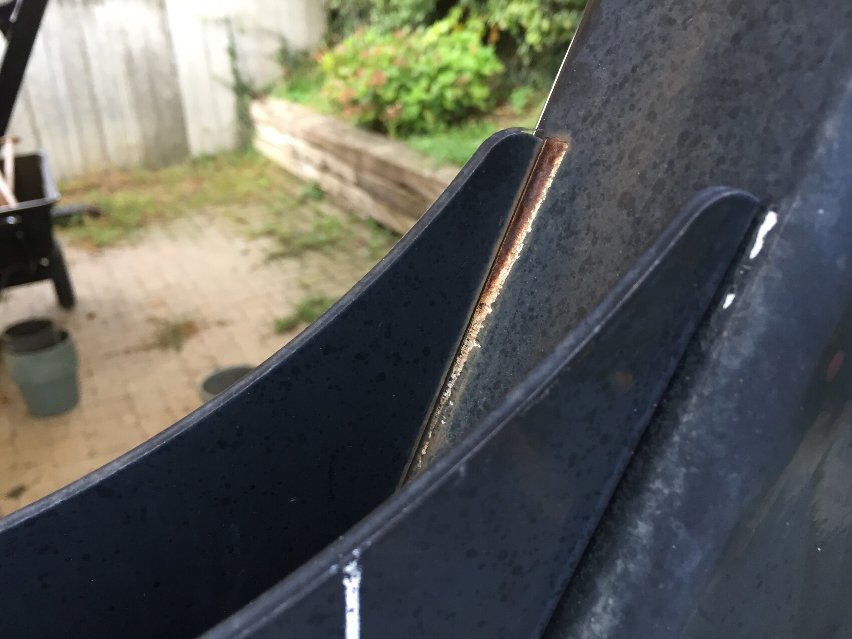 Close-up of a rusty edge on a car door frame, outside in the garden.