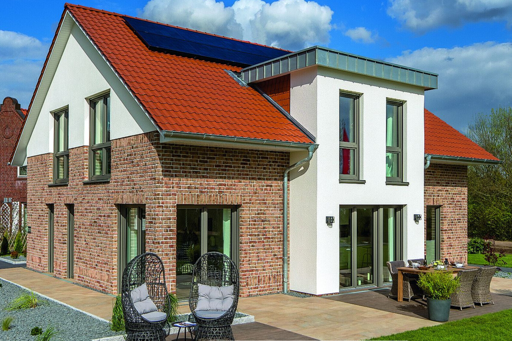 Modern house exterior with red tiled roof, stone facade and terrace