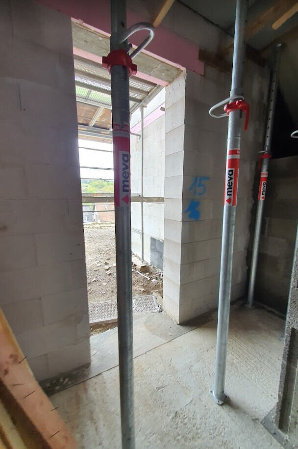 Construction site at shell stage with steel supports, concrete walls and open windows
