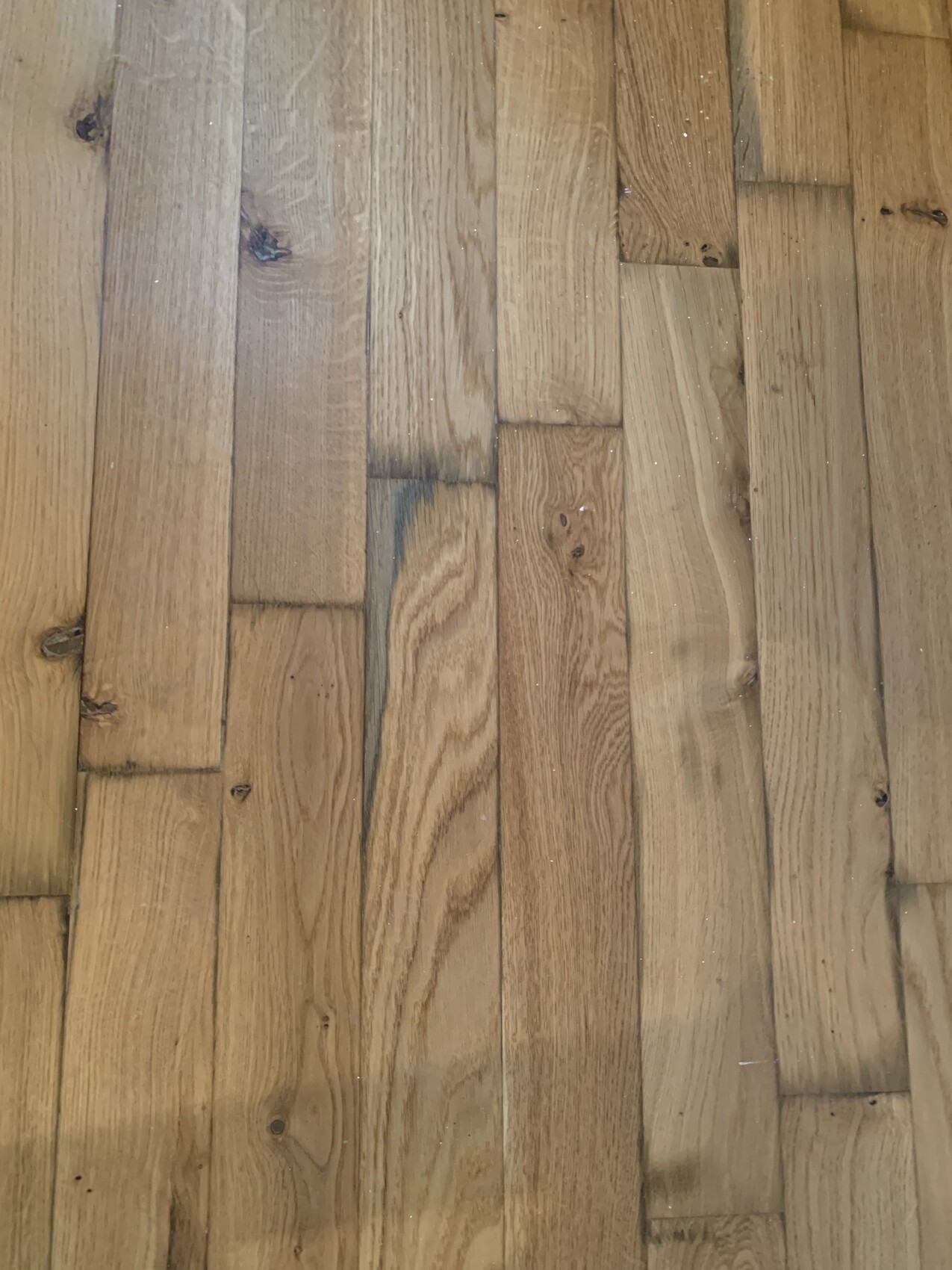 Wood floor made of long planks with grain, knots, and color variations.