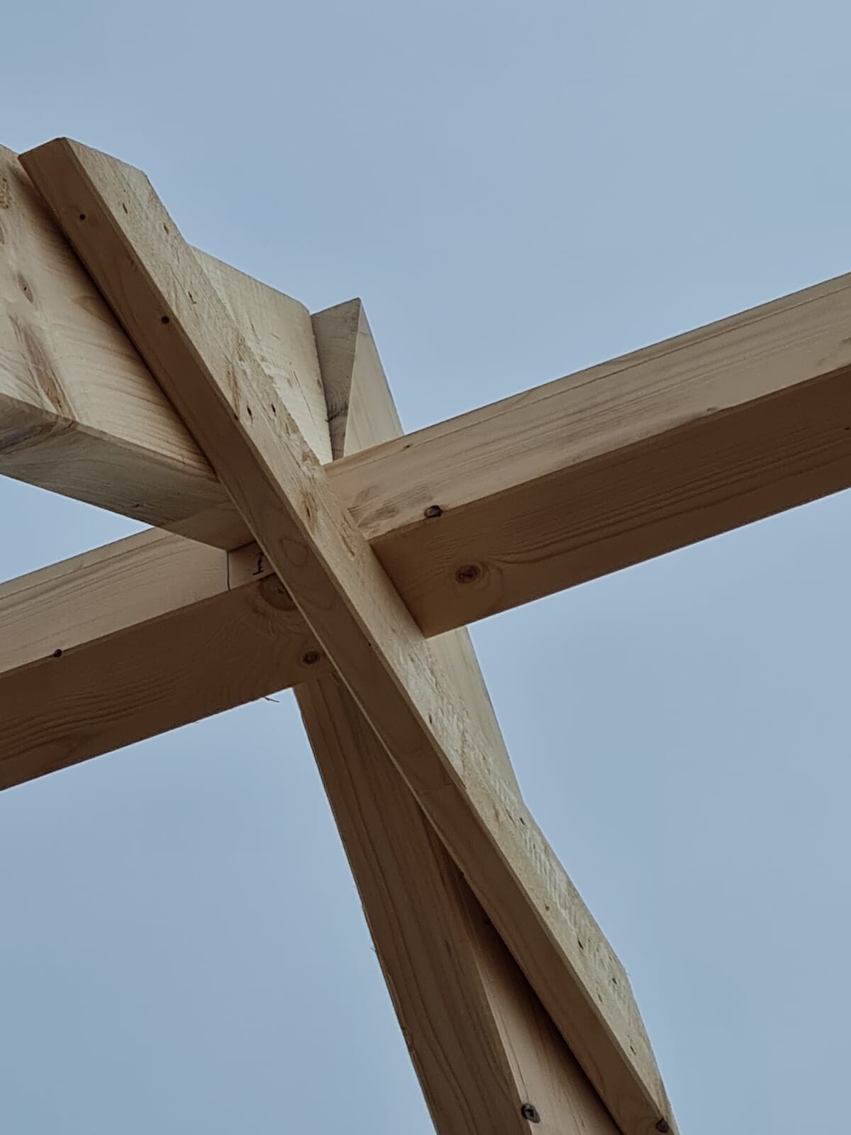 Holz-Balken-Konstruktion mit Kreuzverbindung vor blauem Himmel