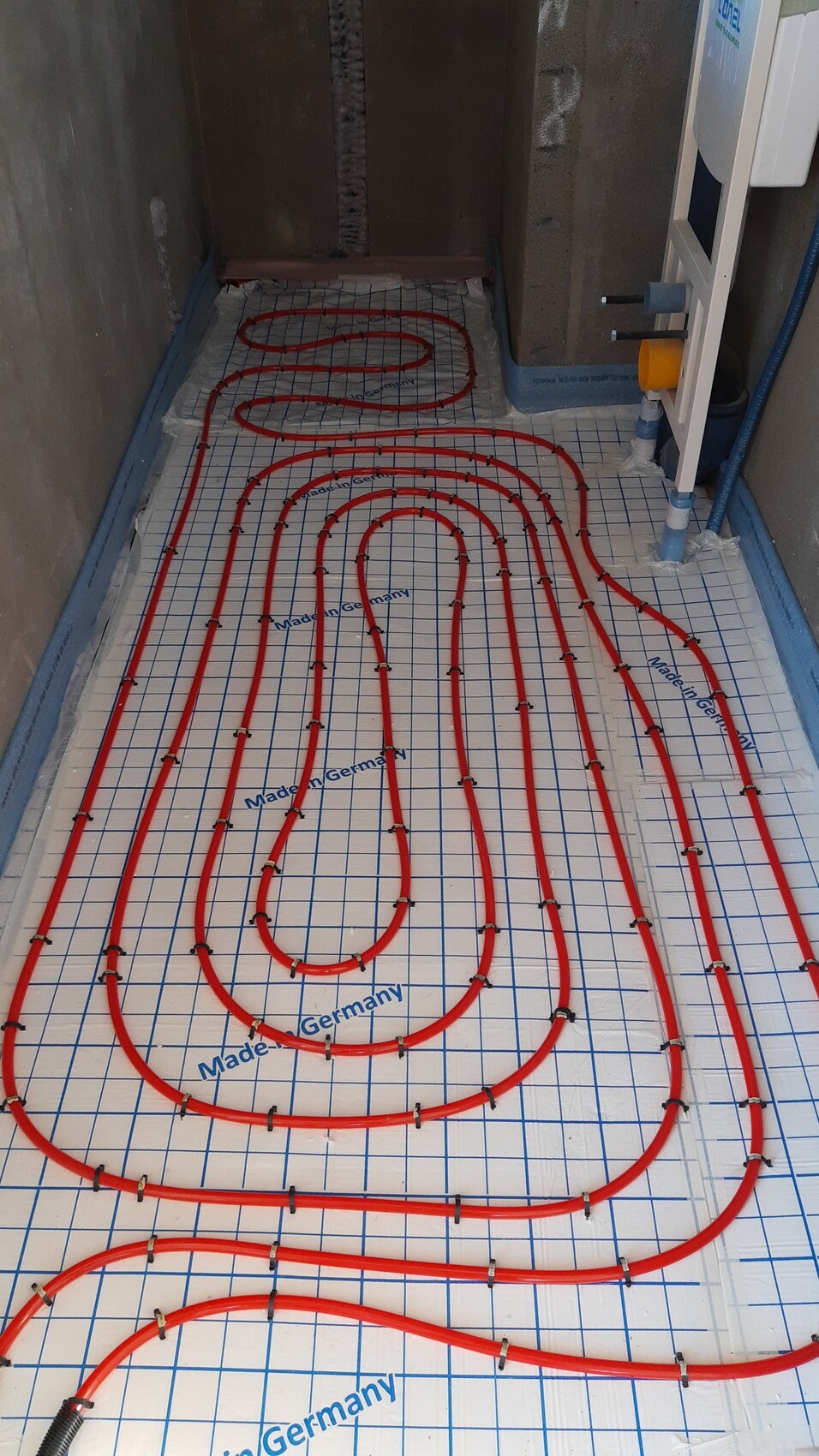 Underfloor heating: red pipes spiraled on insulation layer.