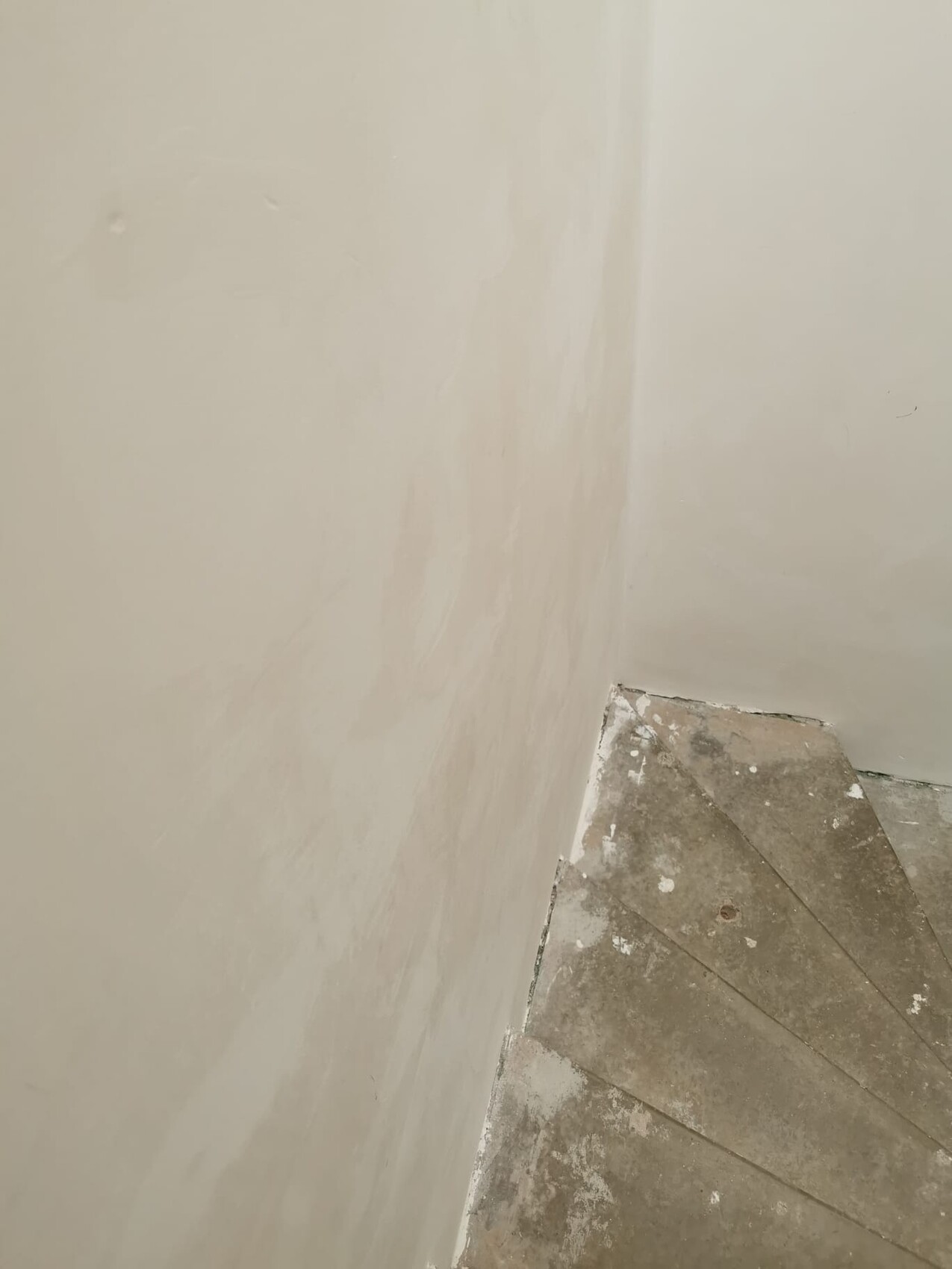 Bright wall area in a corner; right stone steps of a staircase, dusty and worn.