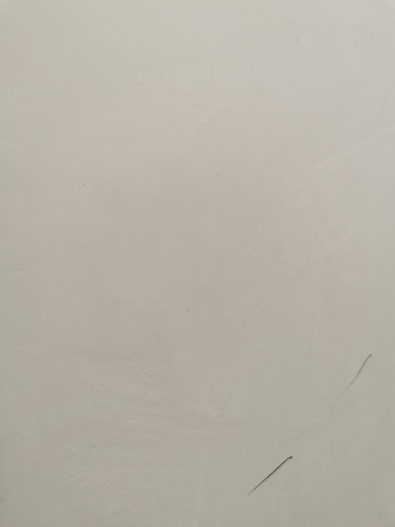 Light cream-colored wall with slight scratches and unevenness.